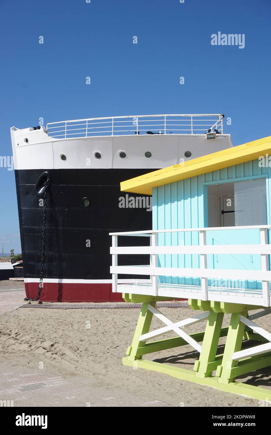 Port-Barcarès, France - October 2022; former cruise ship Le Lydia on beach beside brightly coloured lifeguard tower against backdrop of blue sky Stock Photo