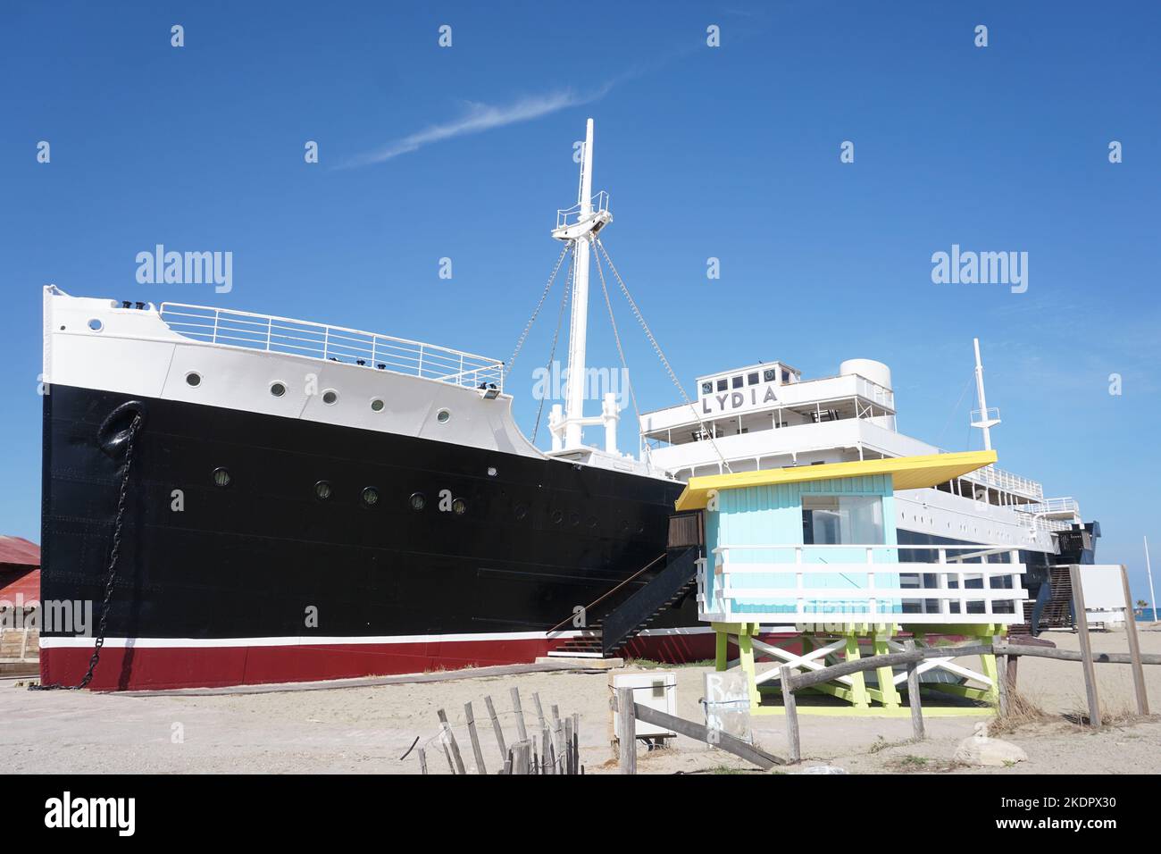 Port-Barcarès, France - October 2022; former cruise ship Le Lydia on beach beside brightly coloured lifeguard tower against backdrop of blue sky Stock Photo