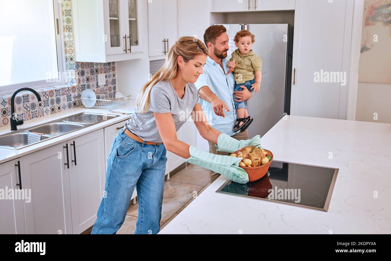 Family, cooking and home kitchen with a mother, father and child waiting for dinner, food and a healthy meal. Man, woman and baby in house for bonding Stock Photo