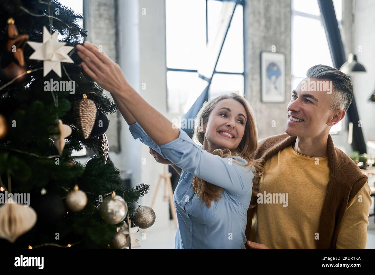Smiling couple decorating xmas tree and looking joyful Stock Photo
