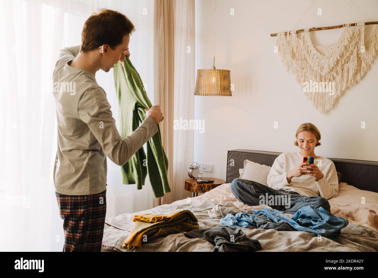 Young gay couple talking and smiling while doing housework at home Stock Photo