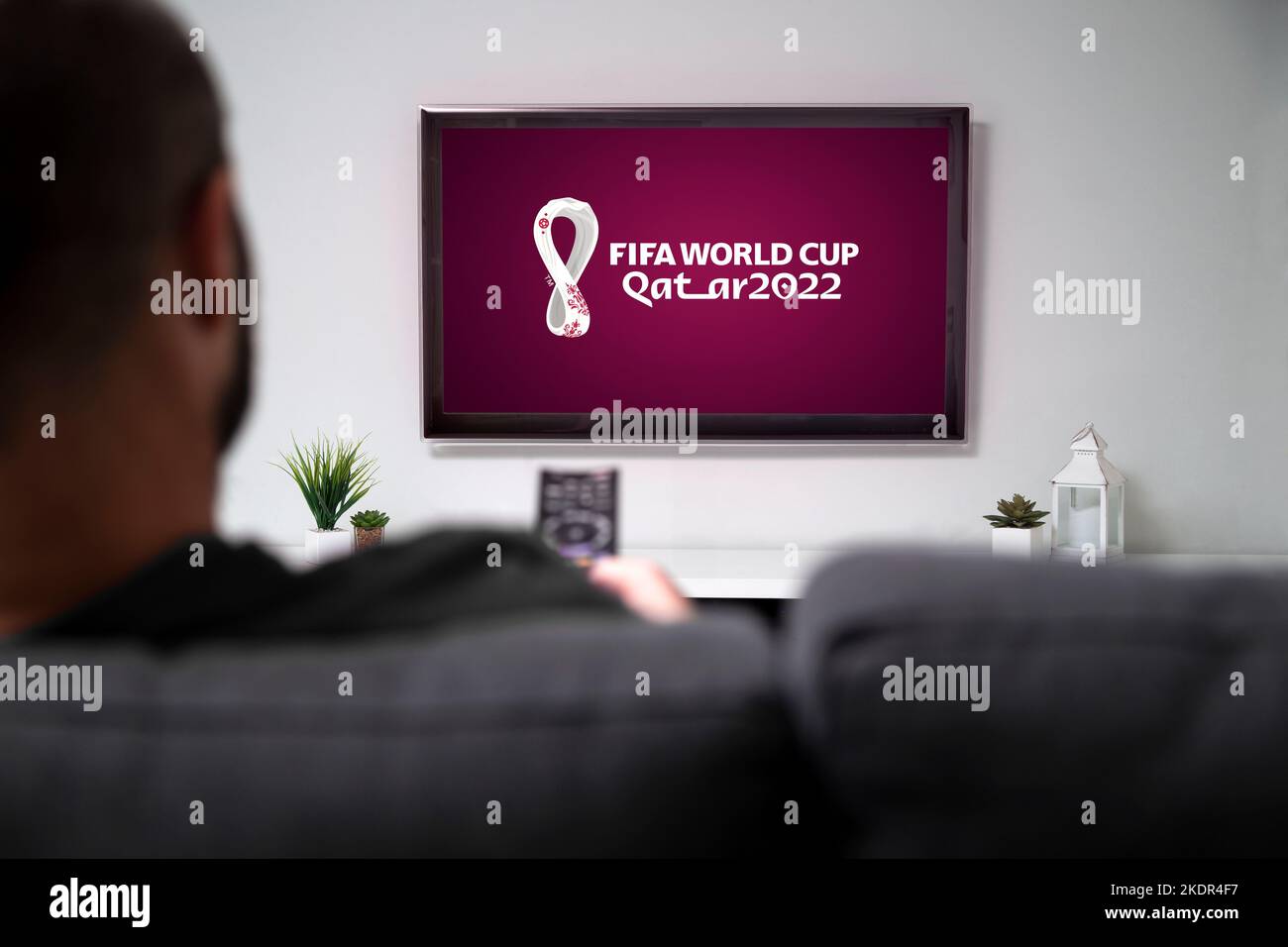 Man looking a smart TV with the QATAR 2022 FIFA World Cup logo in the screen. Doha, Qatar - November 08, 2022. Stock Photo
