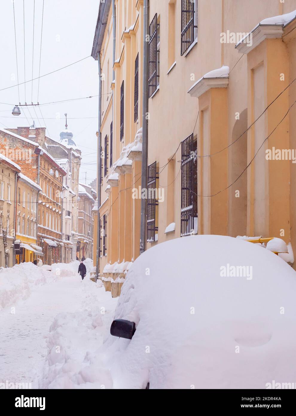 Snow covered street of Lviv old town with cafes and restaurants, car in a huge snowdrift, winter Lviv, Ukraine Stock Photo