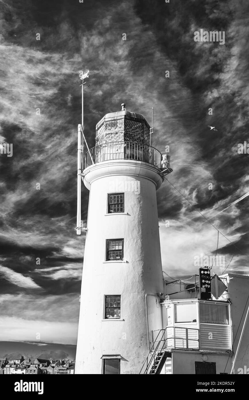 A whitewashed lighthouse stands prominently against a cloud filled sky