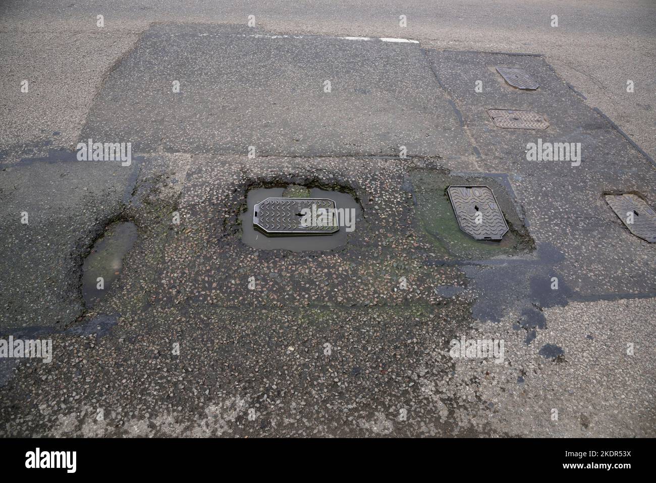 Wash out WO hydrant cover with damage to road surface and water leaking into damaged area Stock Photo