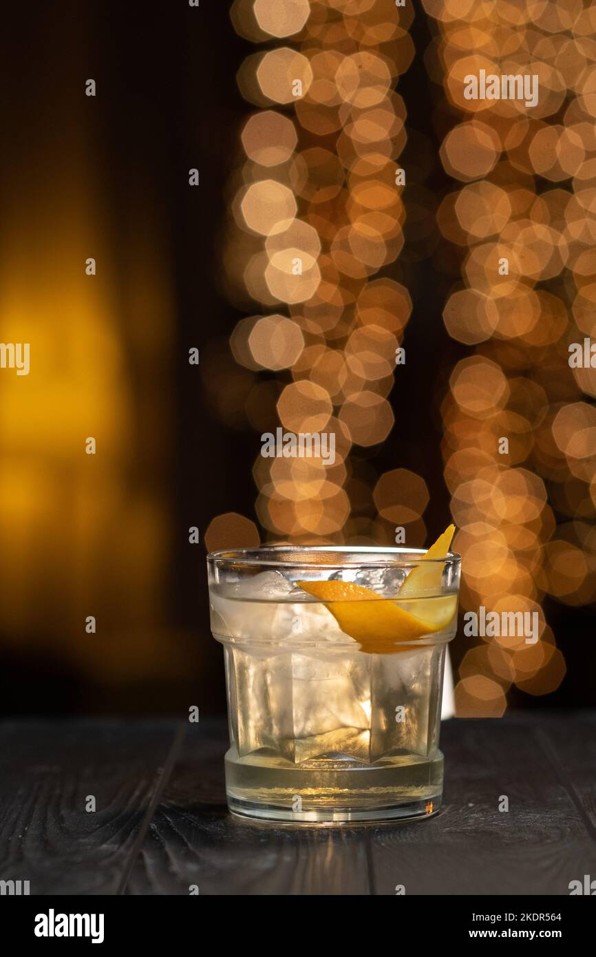 Classic White Cocktail in a glass with ice and orange peel on a brown light background Stock Photo