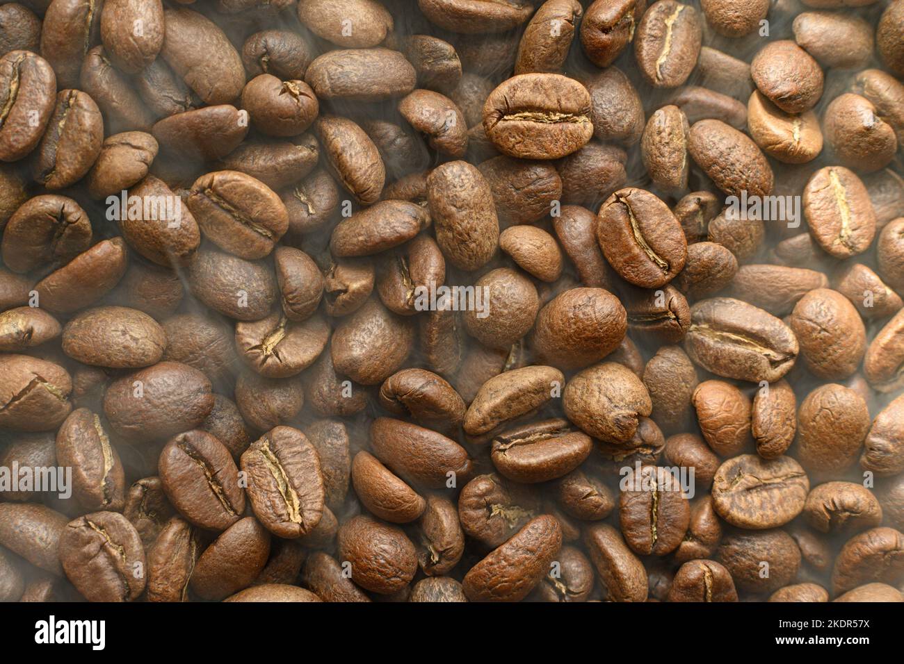 Black coffee beans with light smoke from steam, texture of coffee beans ...