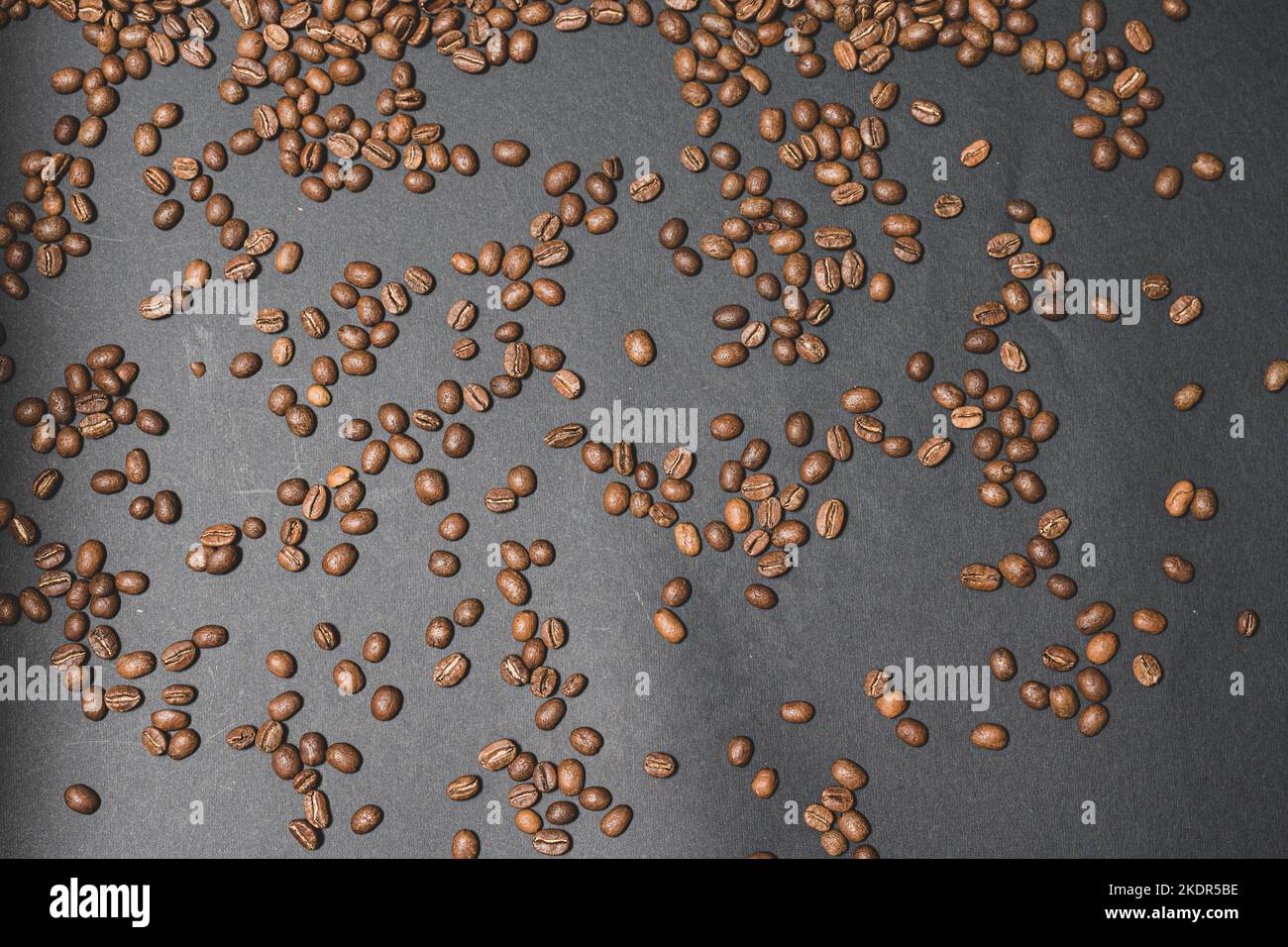 Evenly scattered coffee beans on a black background, roasted brown ...