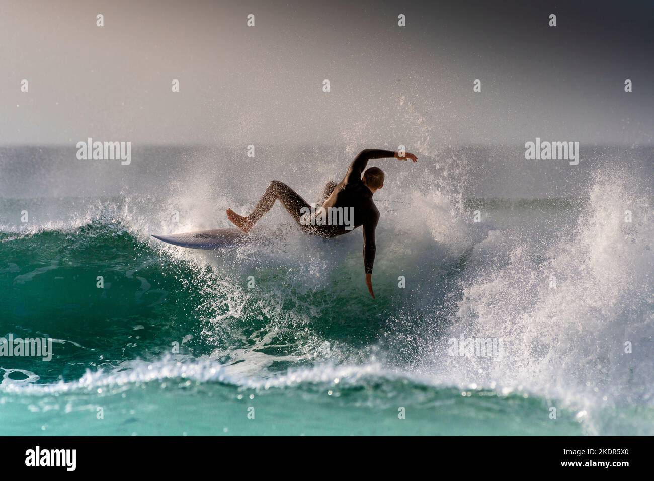 Spectaular surfing action as a male surfer wipes out as he rides a wave at Fistral in Newquay in Cornwall in England in the UK. Stock Photo