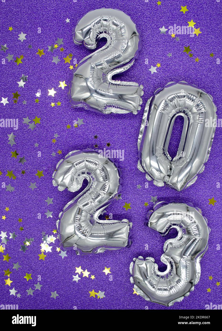 Inflatable shiny silver numbers of the New year 2023 on purple, very peri color background with shiny golden and silver stars. Copy space. Stock Photo