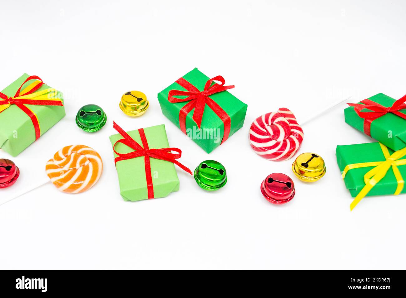 Happy holidays: gifts with lollipops and red, green, golden bells on a white background, copy space. The concept of Christmas, sales, children parties Stock Photo