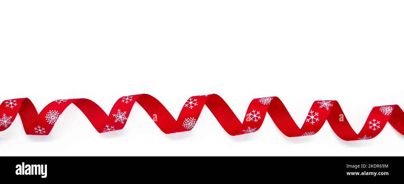 Banner with a red curling bright ribbon with snowflakes on a white background. Copy space. The concept of Christmas, St Valentine Day and gifts. Stock Photo