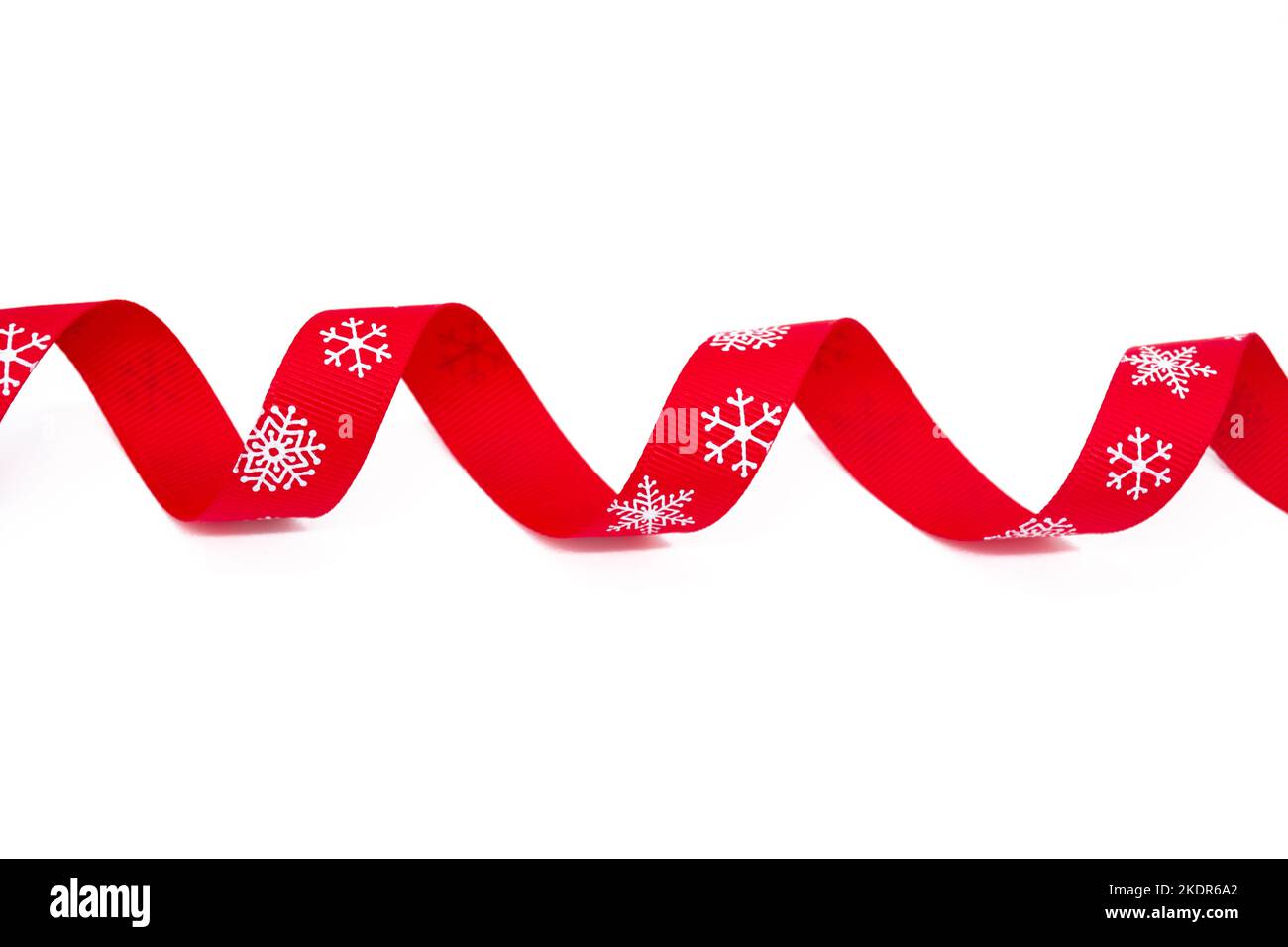 A red curling bright ribbon with snowflakes on a white background. Copy space. The concept of Christmas, St Valentine Day and gifts. Stock Photo