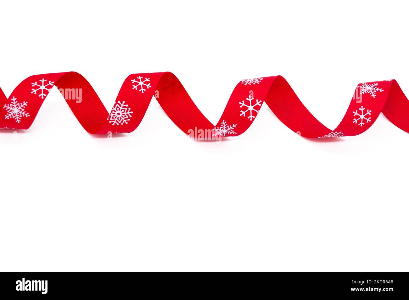 A red curling bright ribbon with snowflakes on a white background. Copy space. The concept of Christmas, St Valentine Day and gifts. Stock Photo