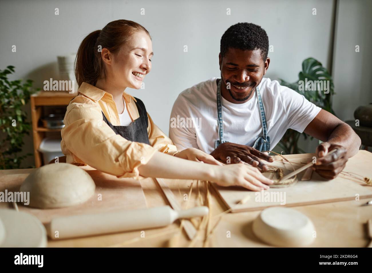 Portrait of carefree young couple enjoying pottery together and making handmade