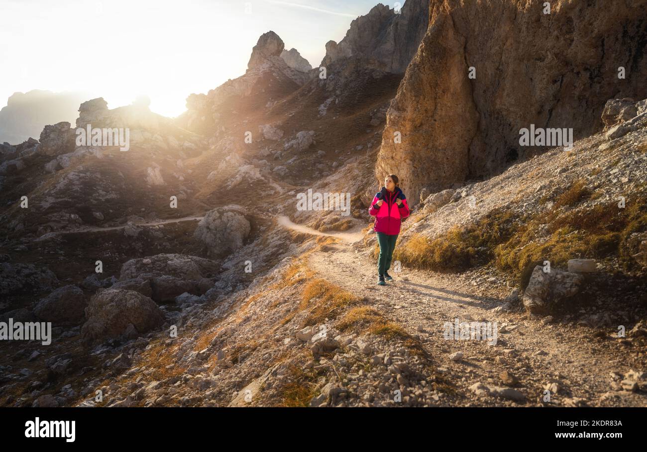 Walking girl with backpack on the trail in mountains at sunset Stock Photo