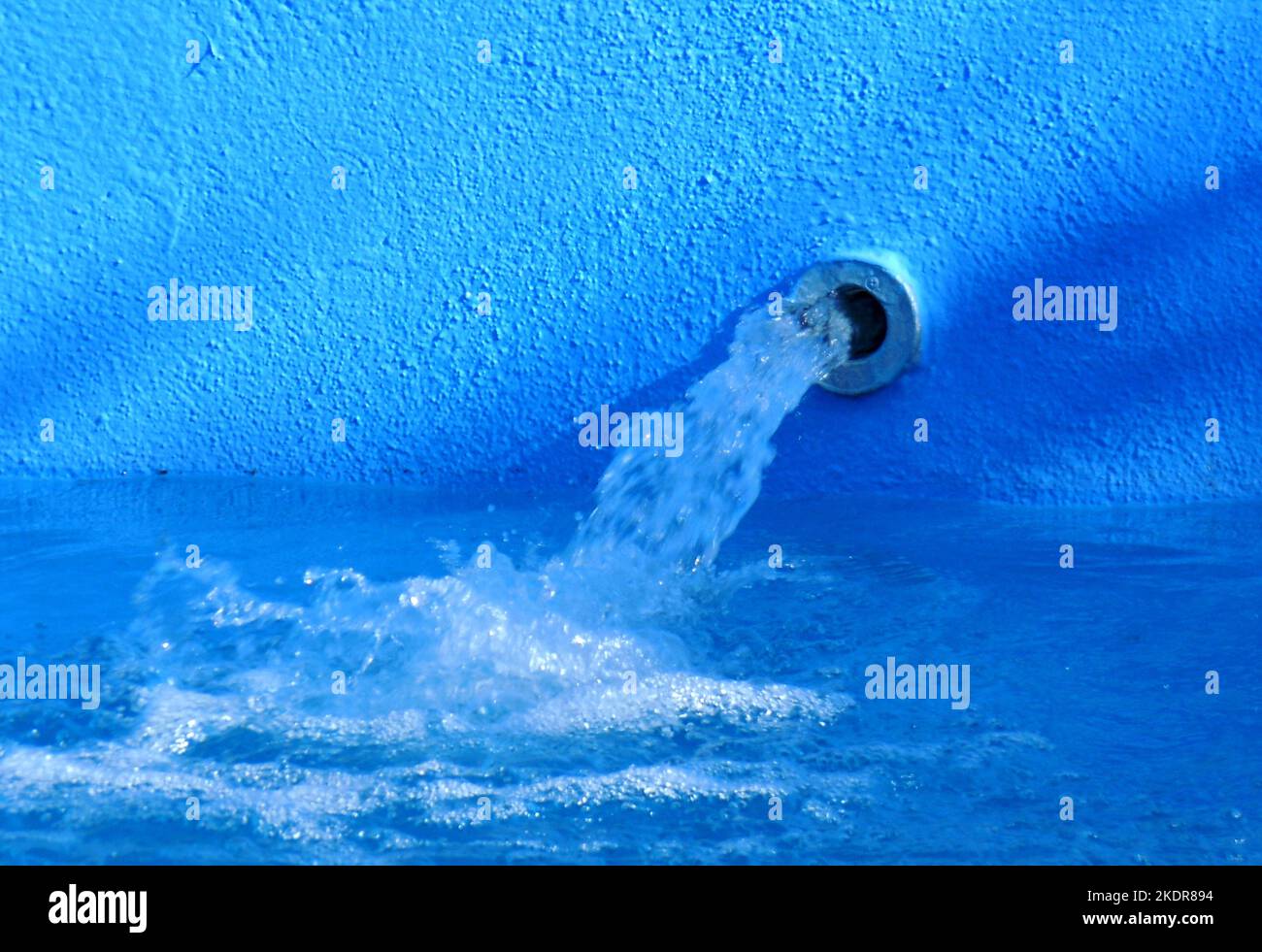 Jet of water coming out of a spout in a swimming pool with walls