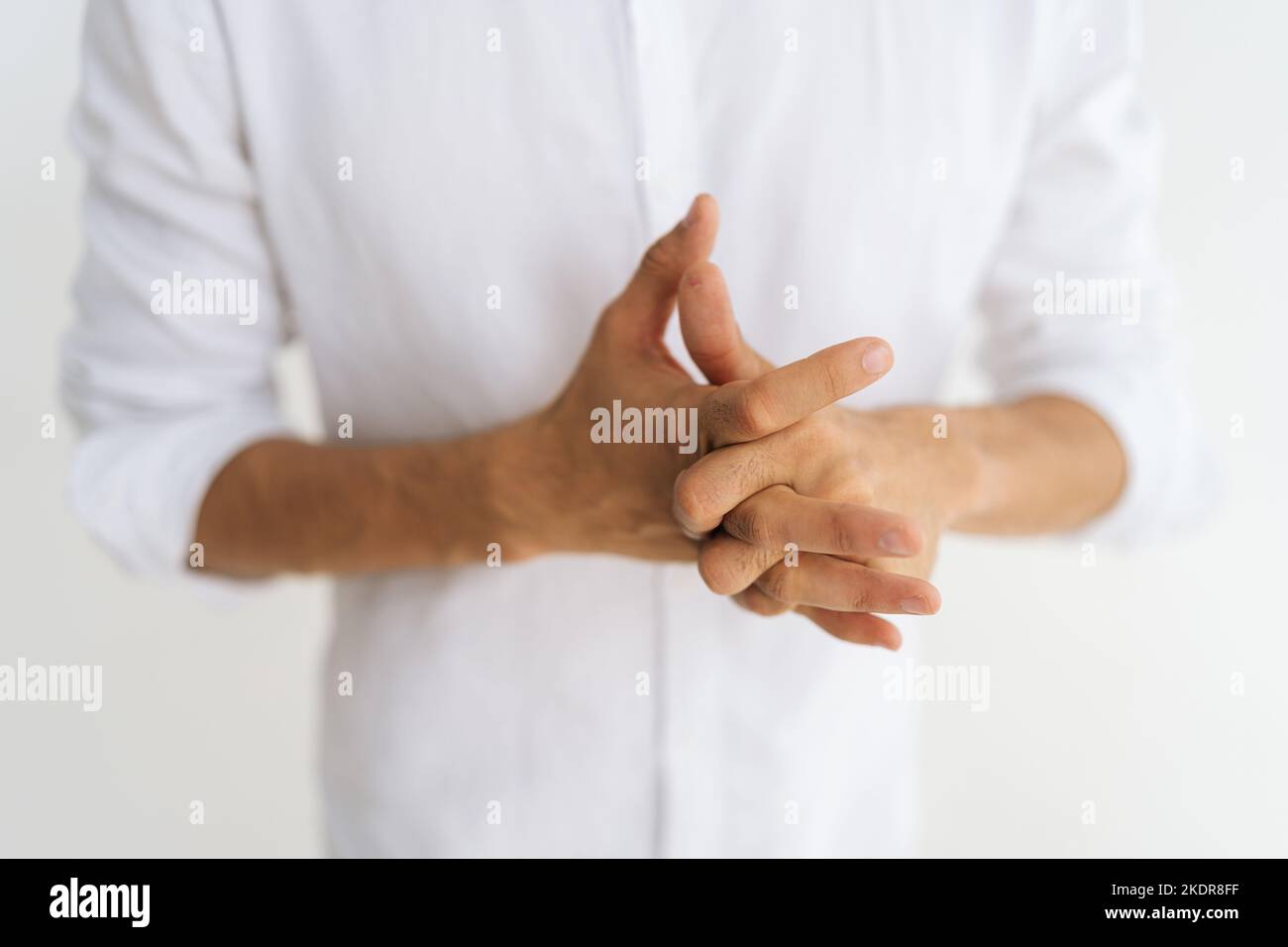 Close-up cropped shot of unrecognizable stressed man suffering from chronic joint rheumatism racking knuckles and fingers feeling nervous on white Stock Photo
