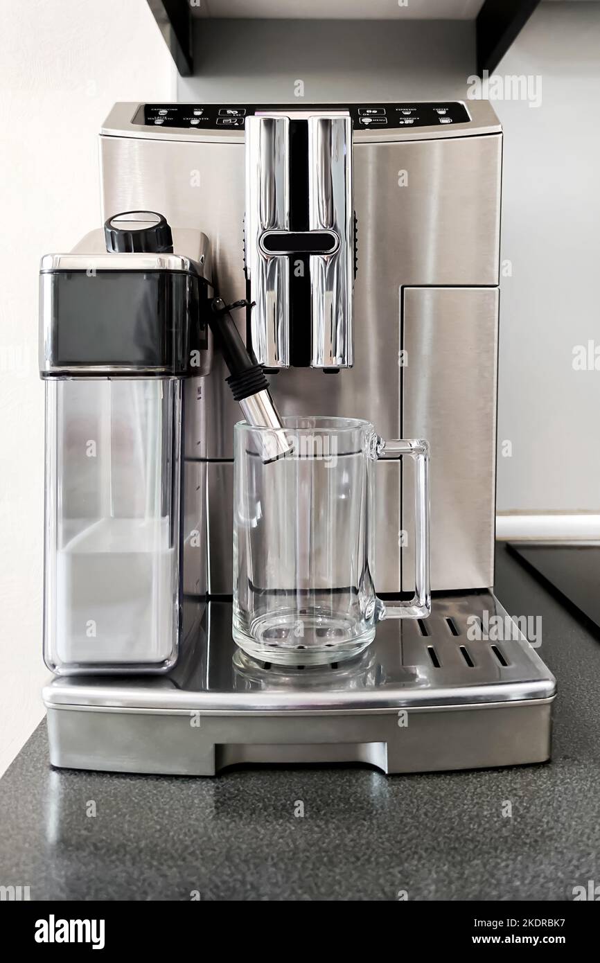 Steelcolored coffee machine for making different types of coffee with glass cup on stand