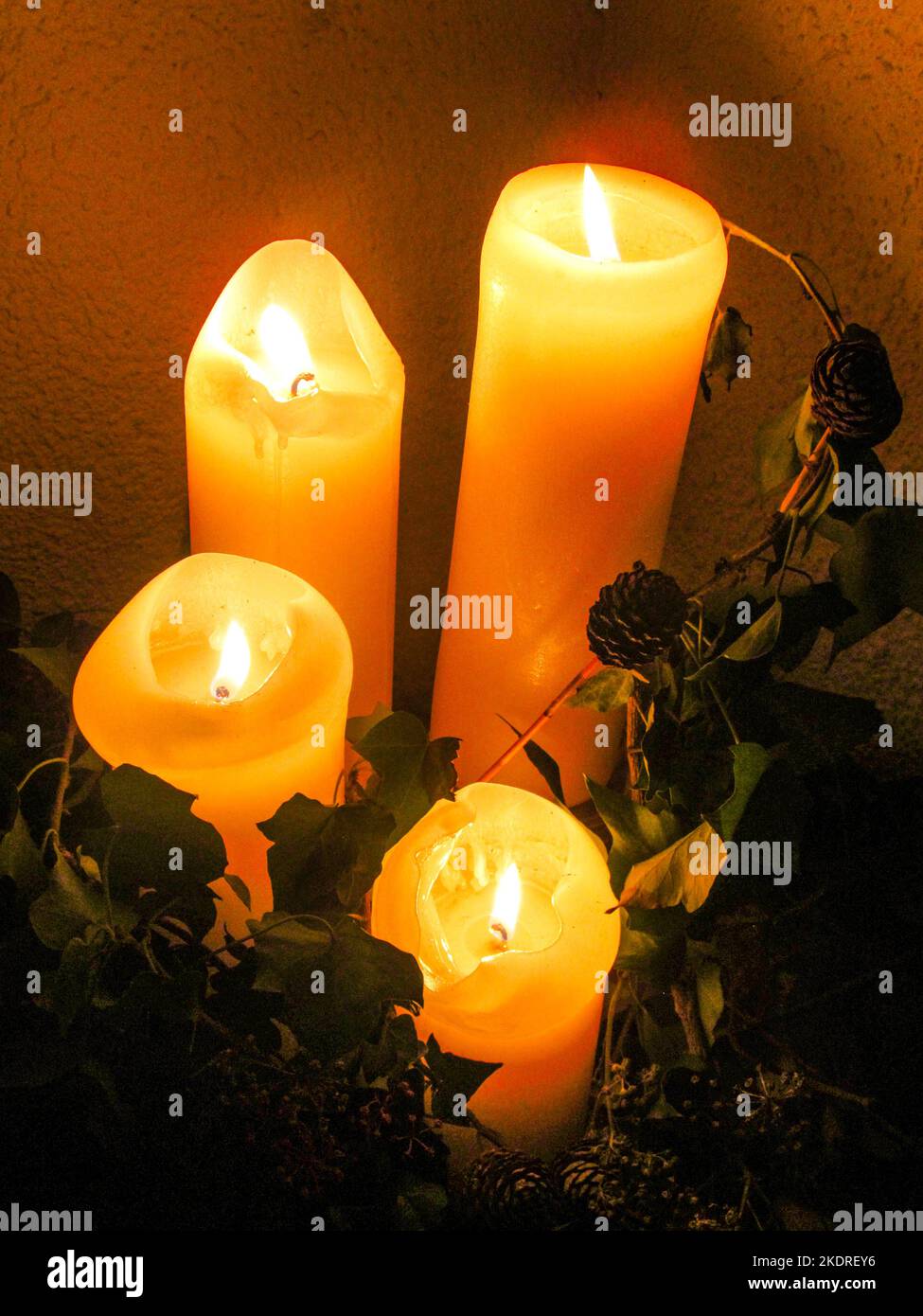 Advent Candles, lit at night, surrounded by dried leaves and seeds