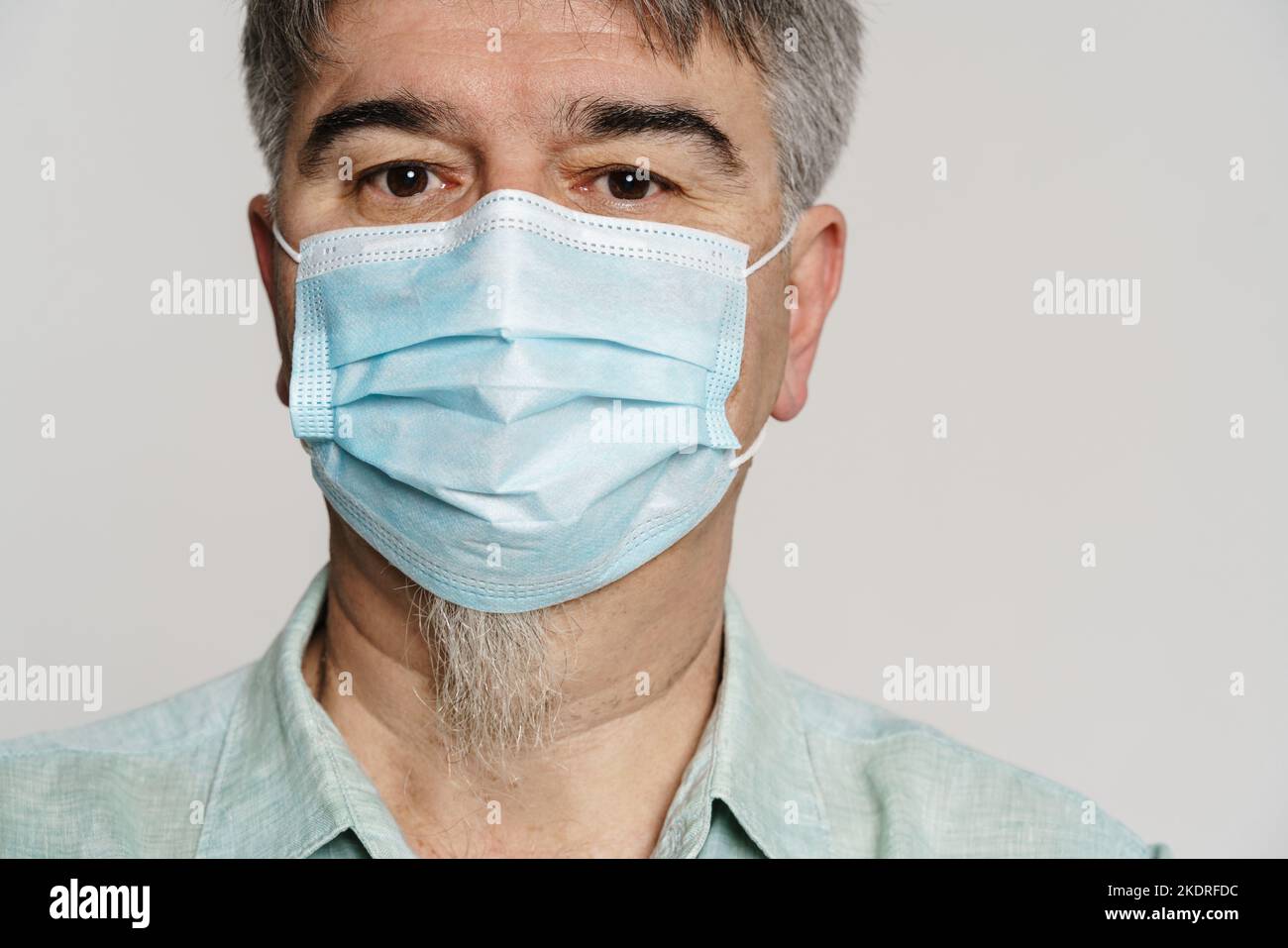 Mature man wearing face mask posing and looking at camera isolated over ...