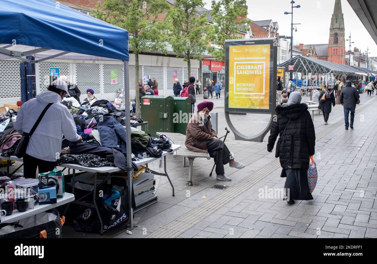 An elderly Sikh man sitting on a bench by the outdoor market in West Bromwich high street. Stock Photo