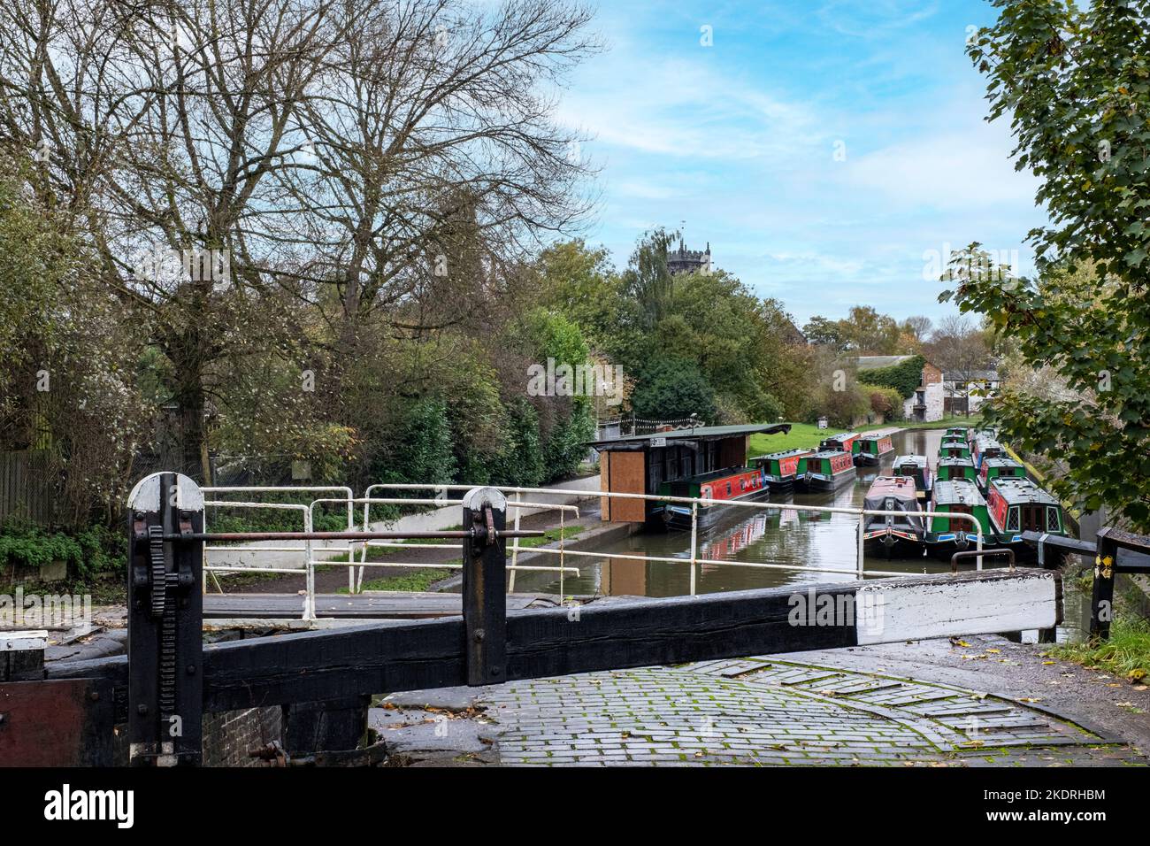 Narrow boats with lock on the Trent & Mersey canal with St Michael Church in distance, Middlewich Cheshire UK Stock Photo