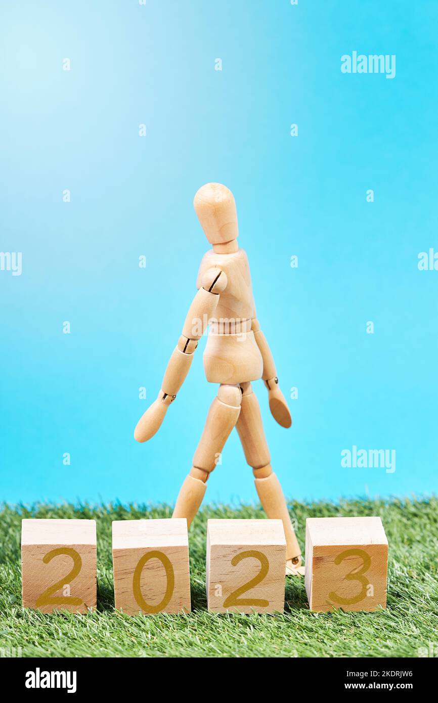 Dummy walking next to cubes with the year 2023 in a grassy meadow. New year concept. Change of year Stock Photo