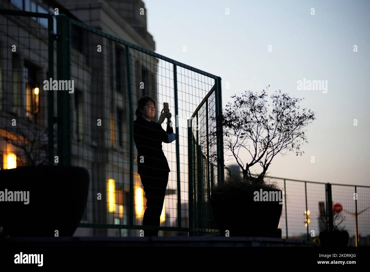 A woman takes pictures of the moon during a lunar eclipse, behind a barrier at a sealed area, following the coronavirus disease (COVID-19) outbreak, in Shanghai, China November 8, 2022. REUTERS/Aly Song Stock Photo