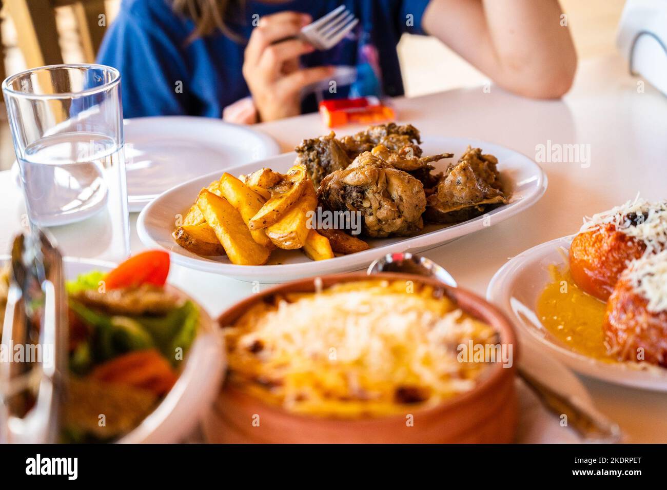 Family eating traditional Greek food in restaurant tavern in Greece. Traditionally served greek food in a greek tavern on authentic dinner tables and Stock Photo