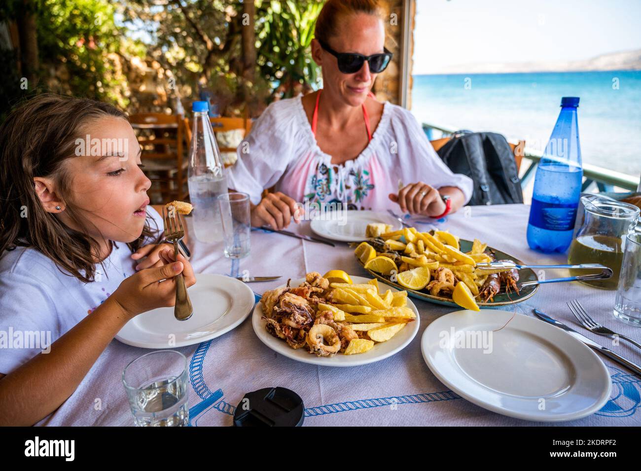 Family eating traditional Greek food in restaurant tavern in Greece. Traditionally served greek food in a greek tavern on authentic dinner tables and Stock Photo