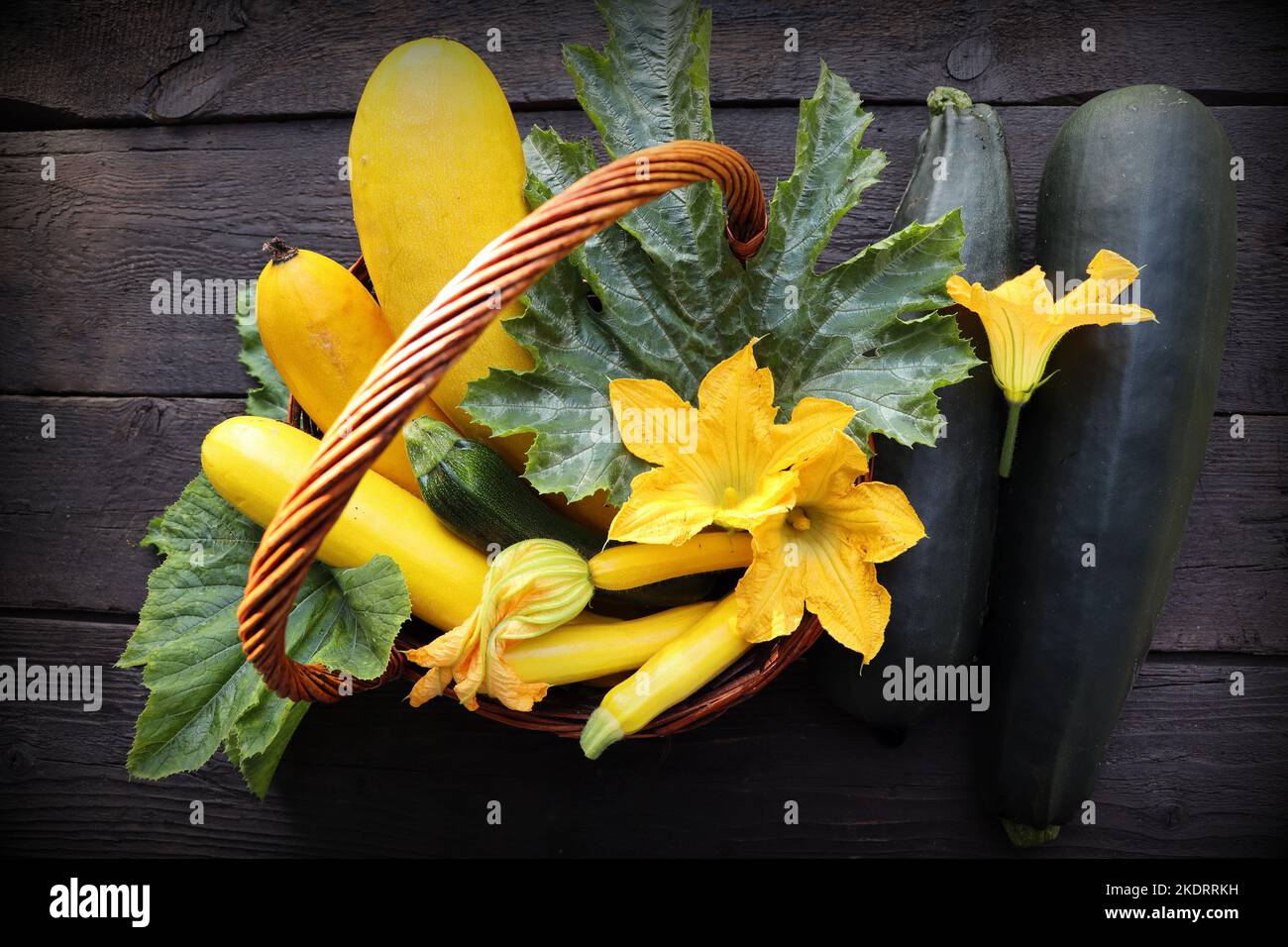 Harvest of fresh green and yellow zucchini . Zucchini with flowers on the old rustic dark wooden table Stock Photo