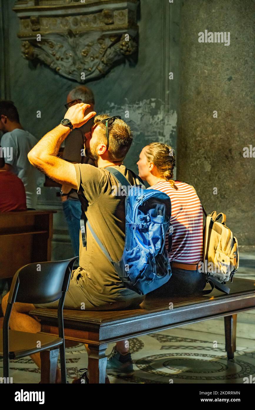 Italian church interior with two young adults looking at the decorative features. Stock Photo