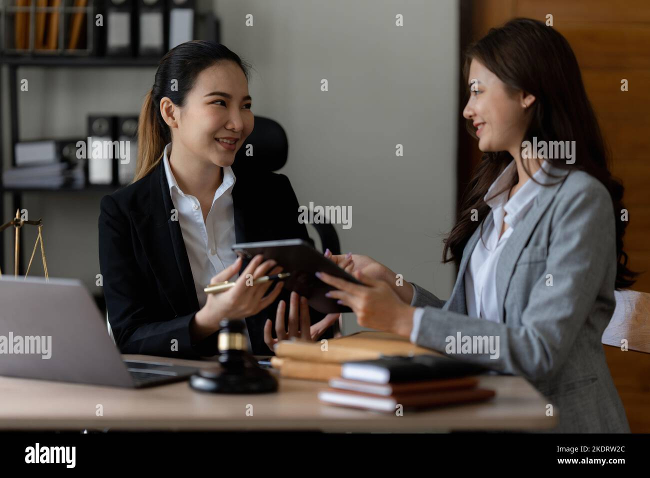 Business woman and lawyers discussing contract papers with brass scale
