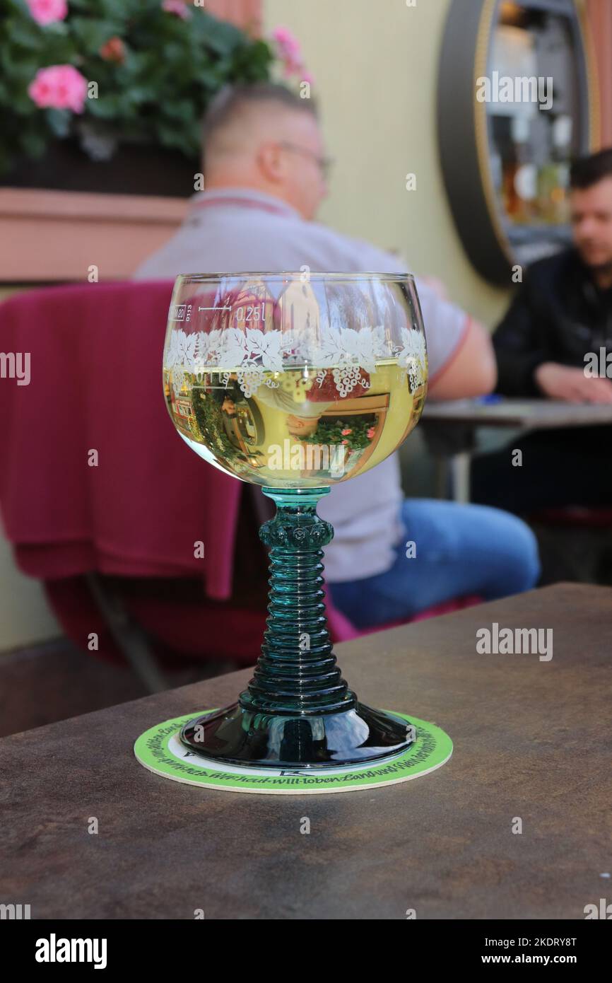 retro vintage Weinglas Römer mit grünem gerilltem Griff und grünem Fuß, Glas graviert, gefüllt mit Silvaner, auf der Terasse einer Weinstube Stock Photo