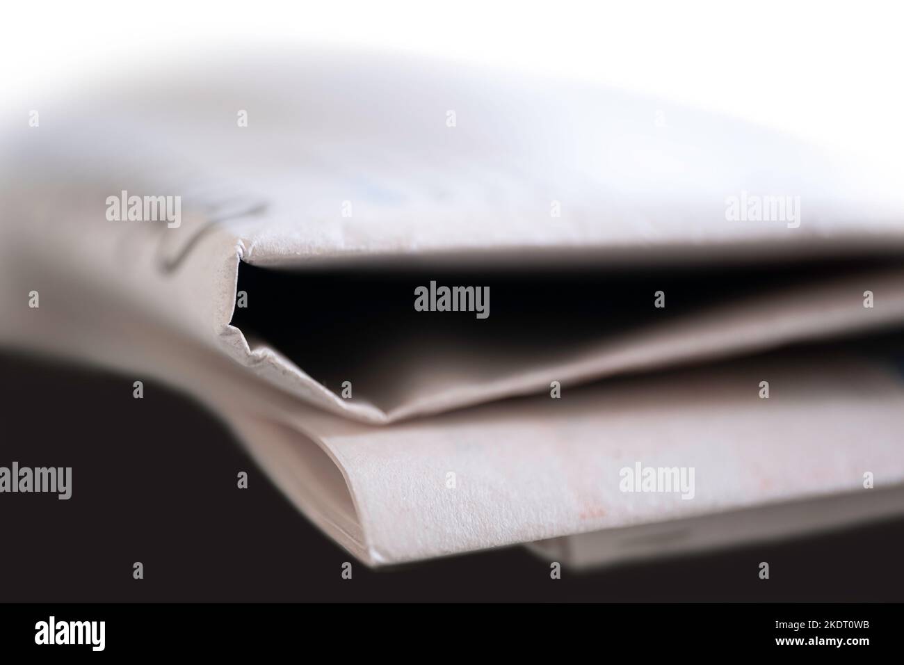 Folded newspaper on a black table with narrow depth of field Stock Photo