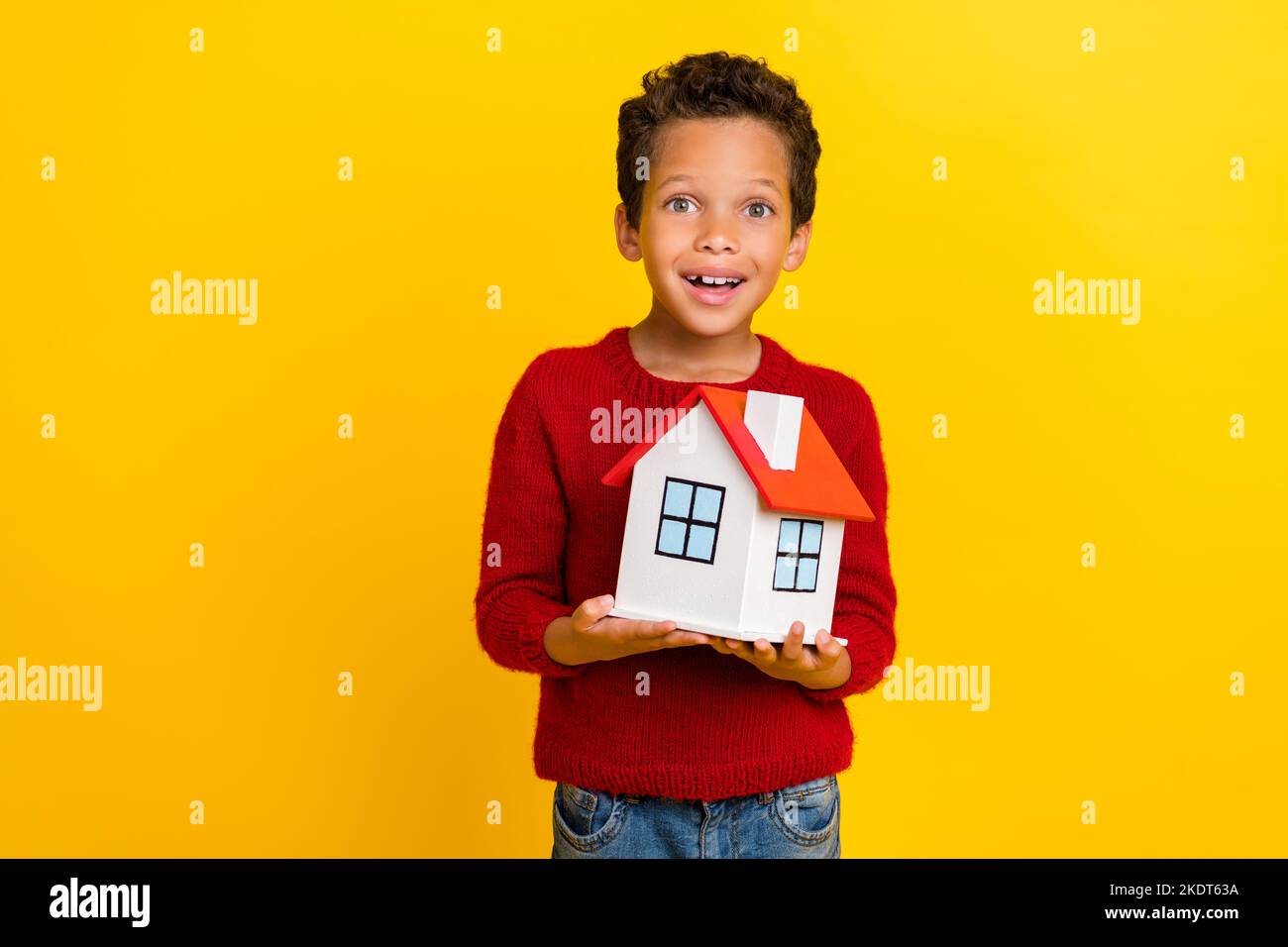 Photo portrait of adorable small boy excited hold mini house insurance dressed stylish red knitted look isolated on yellow color background Stock Photo