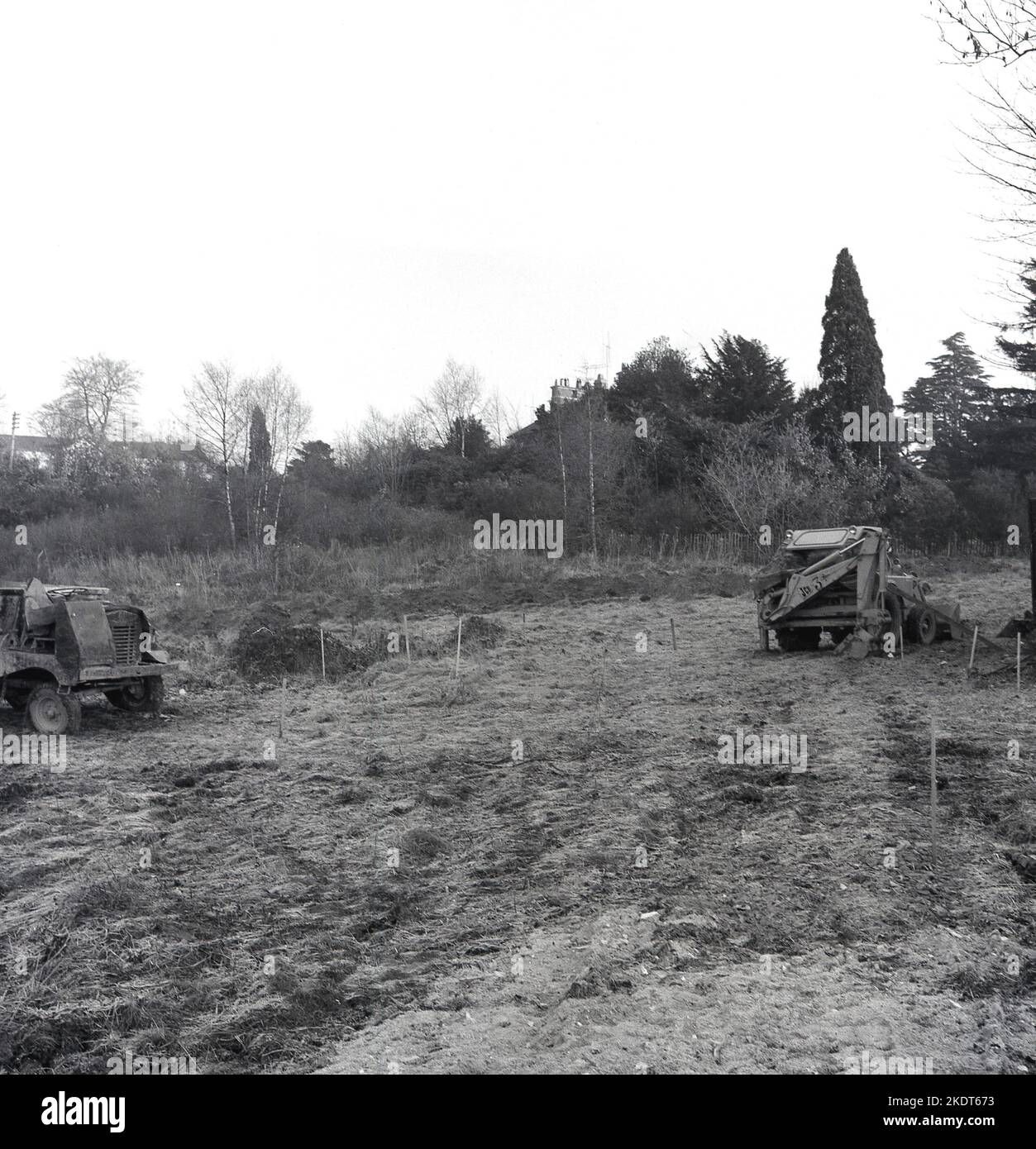 1960s, historical, rural land being cleared, posts marking area, England, UK. Seen in the picture, a JCB 3 backhoe loader. Introduced in 1962 this iconic digger is said to have revolutionised the building industry, with its loader-style shovel on the front and a backhoe on the back. Stock Photo