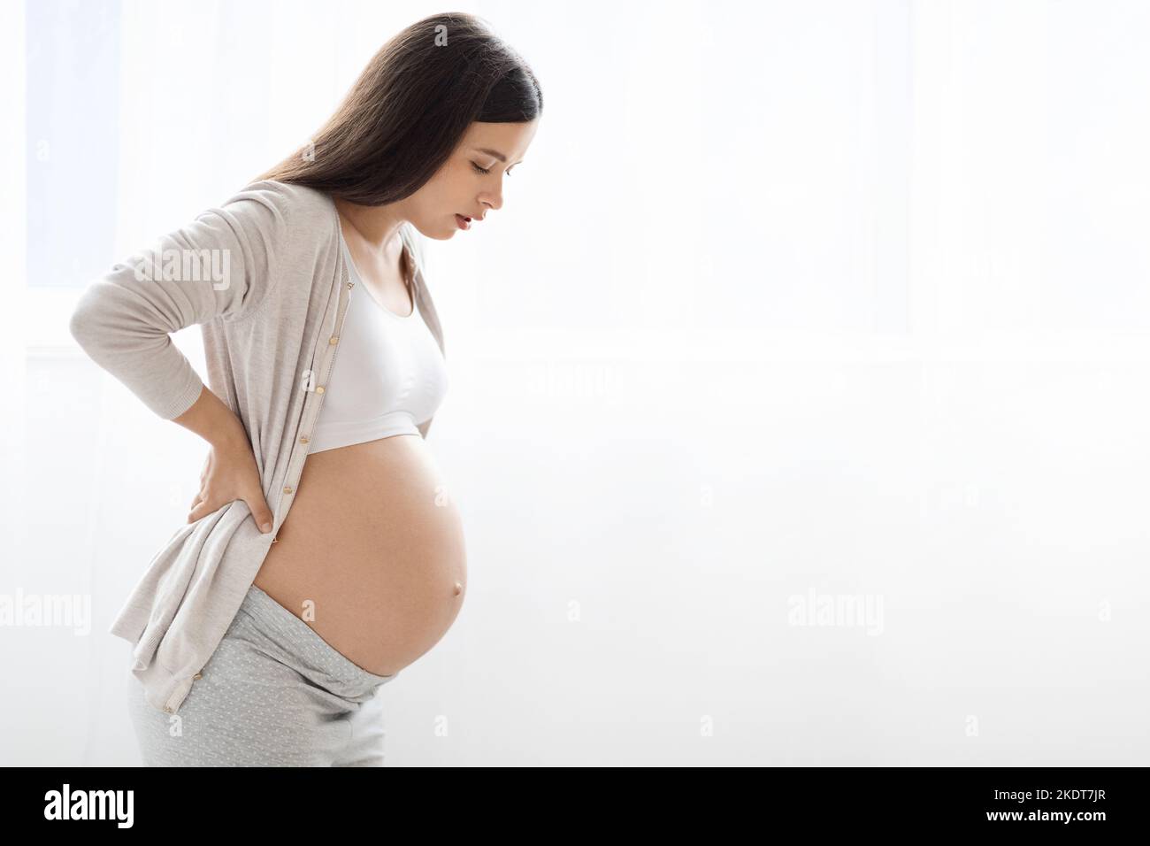 Pregnant lady having back pain over white background Stock Photo