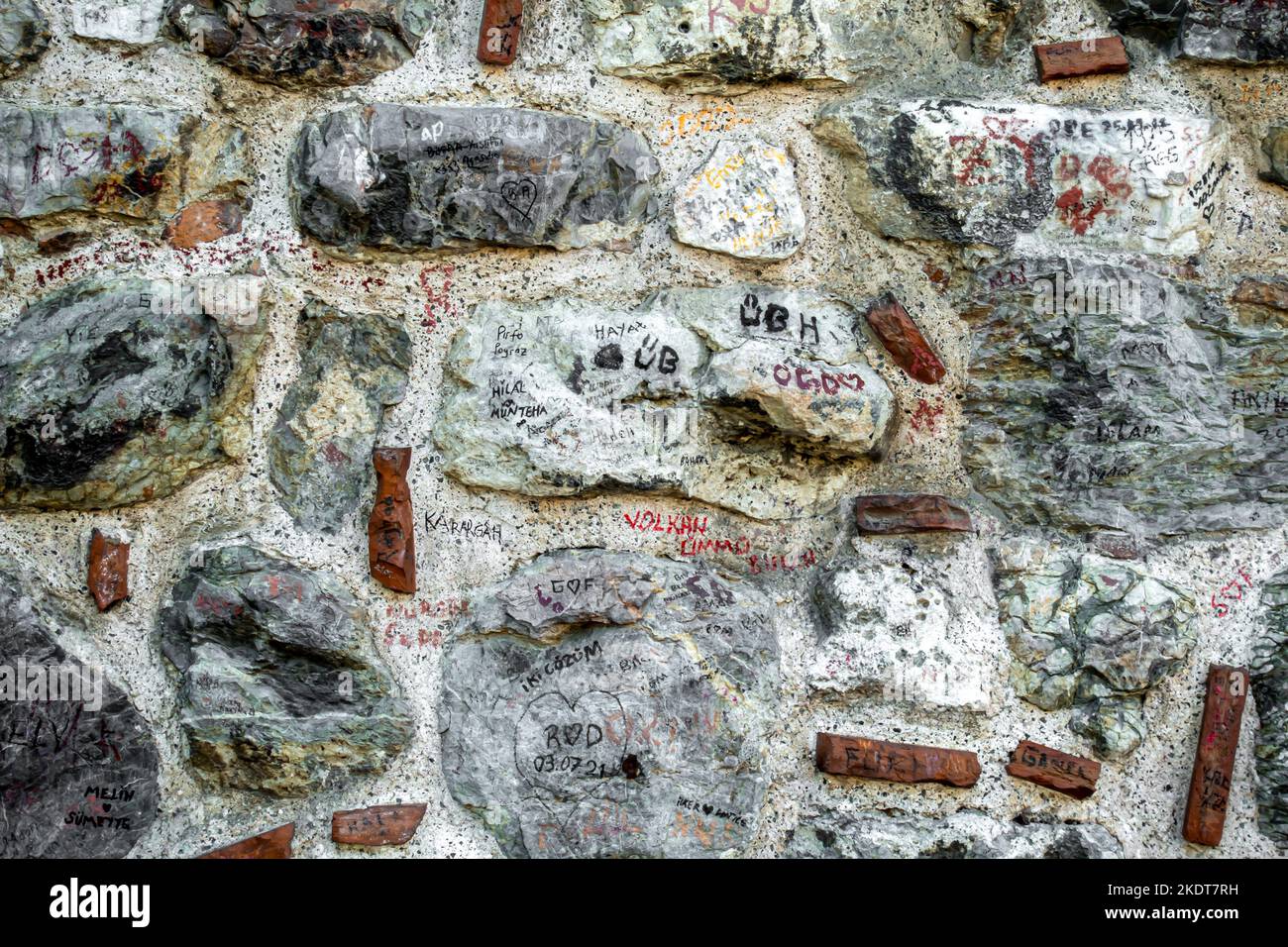 Historic stone wall with tourists inscriptions, marks. Galata tower ...
