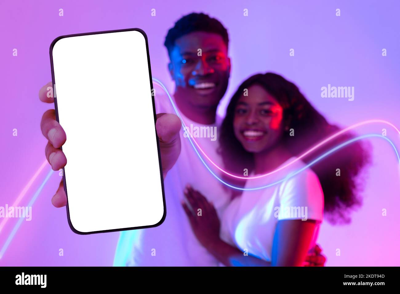 Happy black lovers hugging and showing smartphone with empty screen