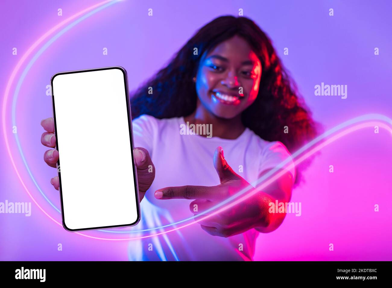 Happy african american woman pointing at smartphone with empty screen ...