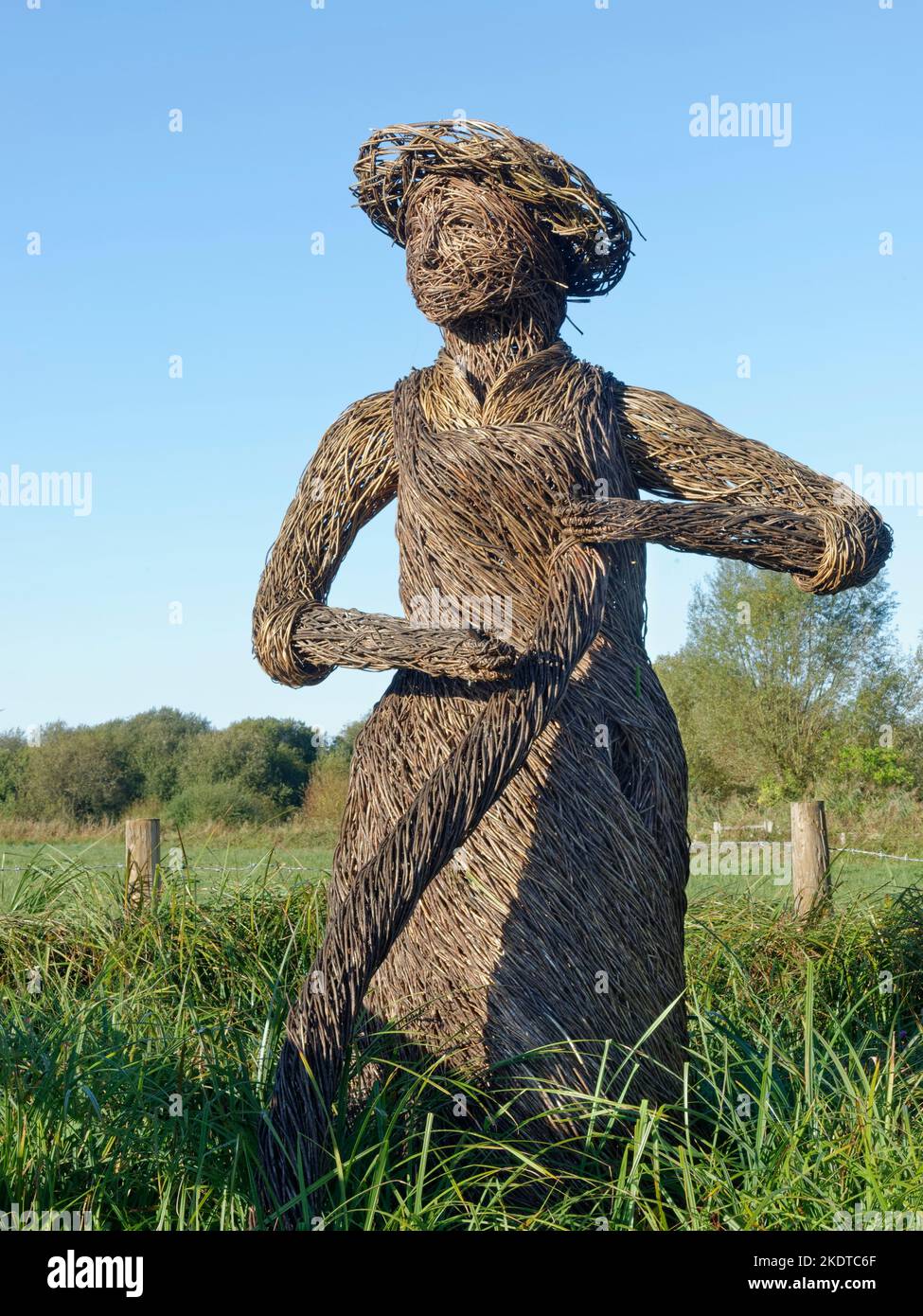Wicker sculpture of a “Brinker” using a scythe to cut vegetation on the Gwent Levels, Magor Marsh reserve, near Newport, Gwent, Wales, UK, March. Stock Photo