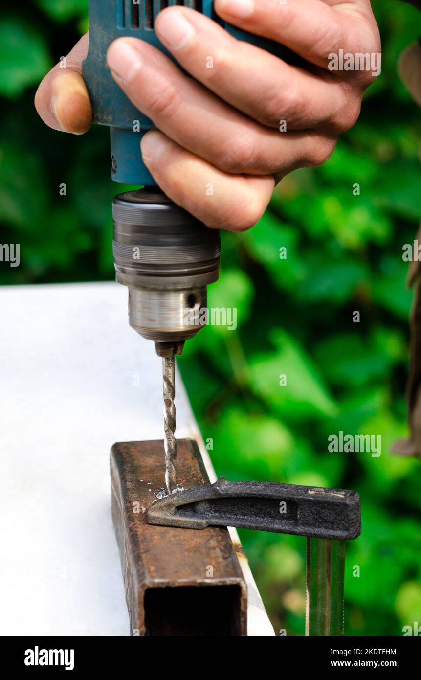 Working with metal. Men's hands with a drill Stock Photo - Alamy