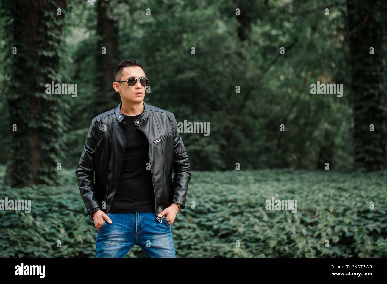 Portrait of a handsome brutal man in a black leather jacket in a dark ...
