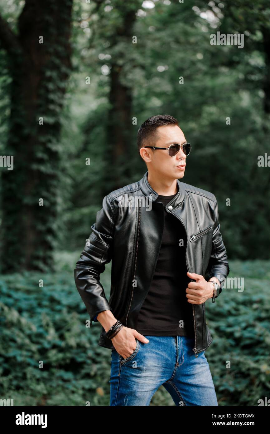 Portrait of a handsome brutal man in a black leather jacket in a dark ...