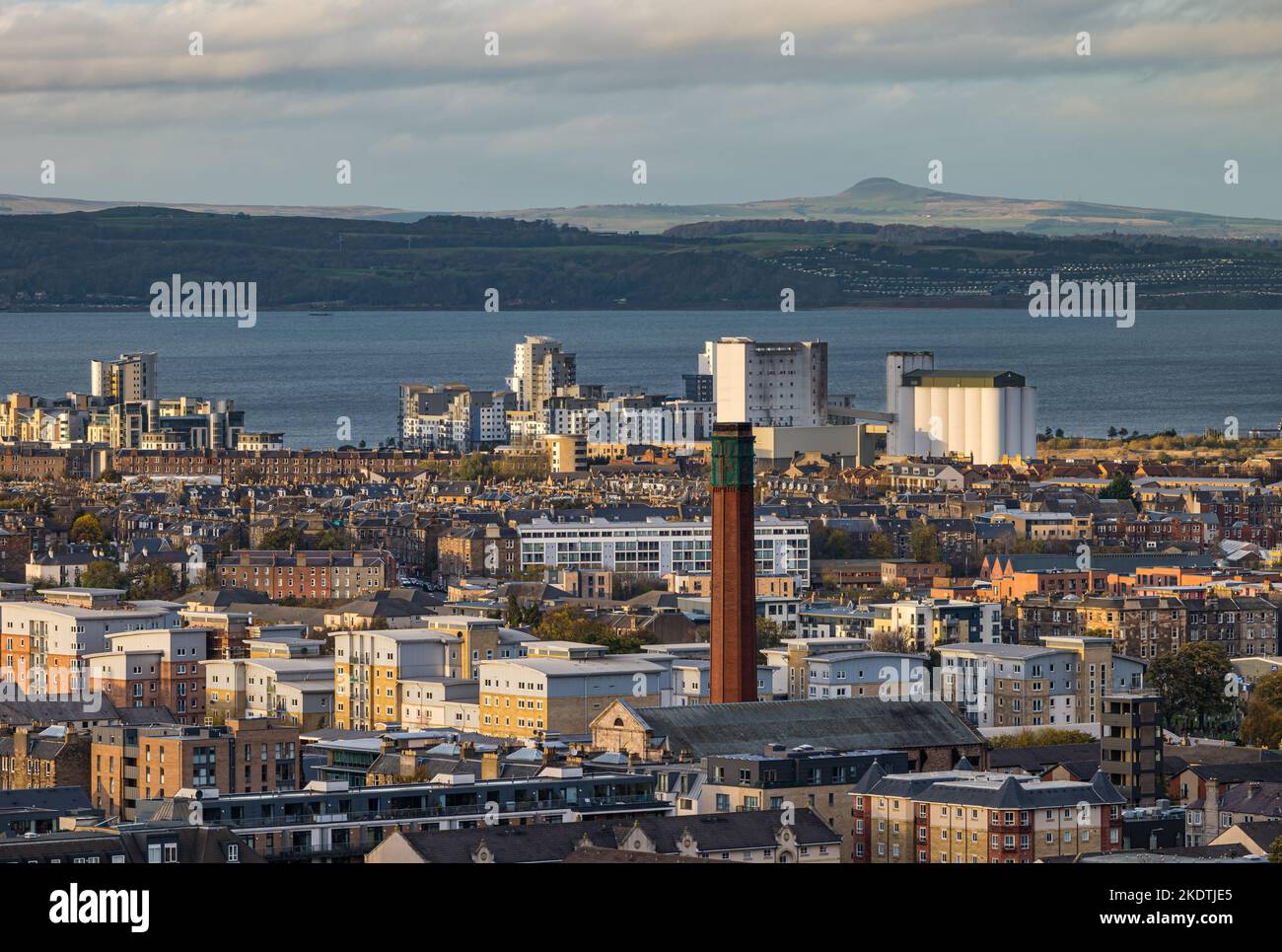 View over rooftops to Firth of Forth, with industrial chimney tower and high rise apartment buildings. Edinburgh, Scotland, UK Stock Photo