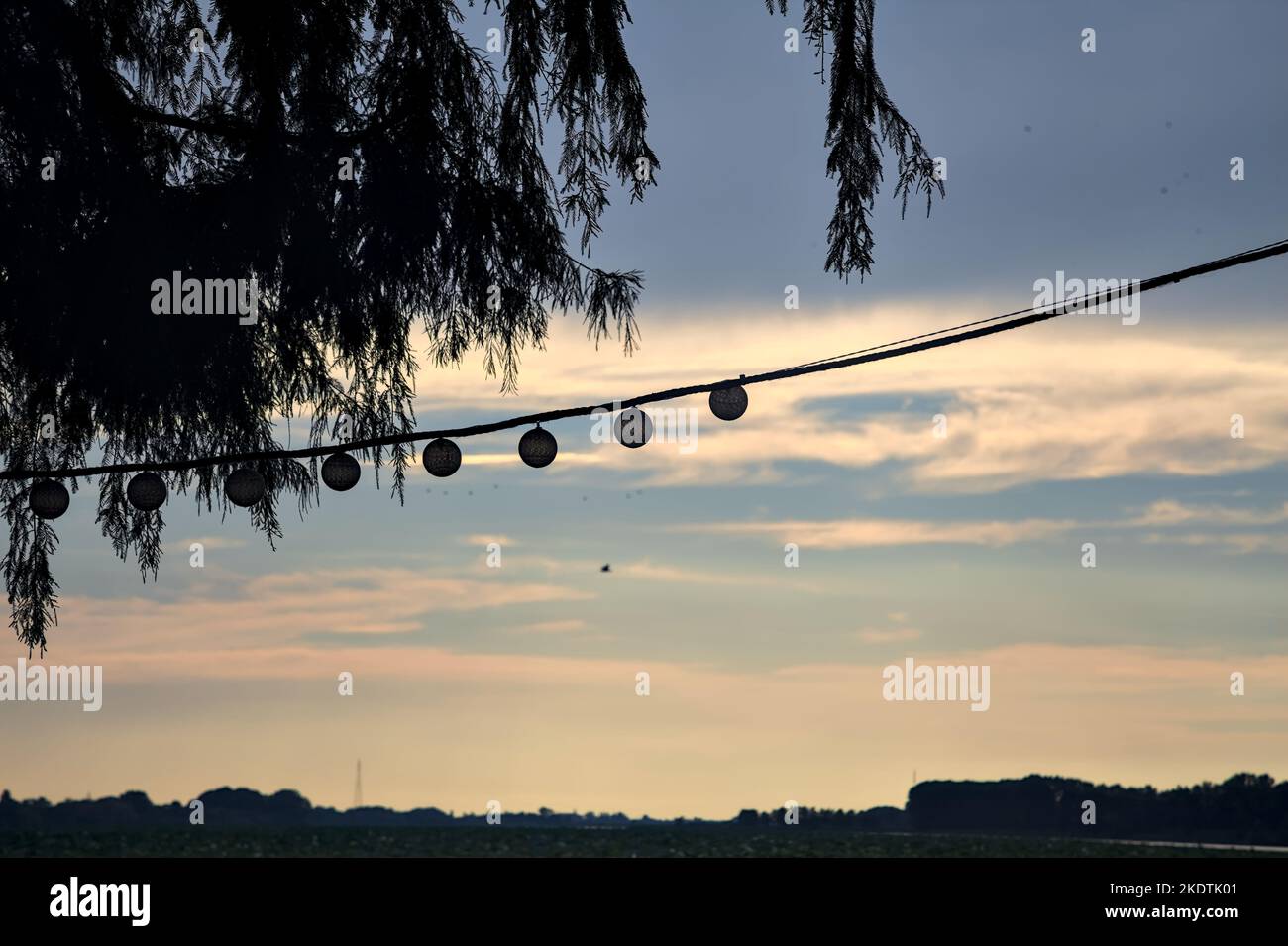 Lights  hanging on a rope with the sunset sky as background Stock Photo