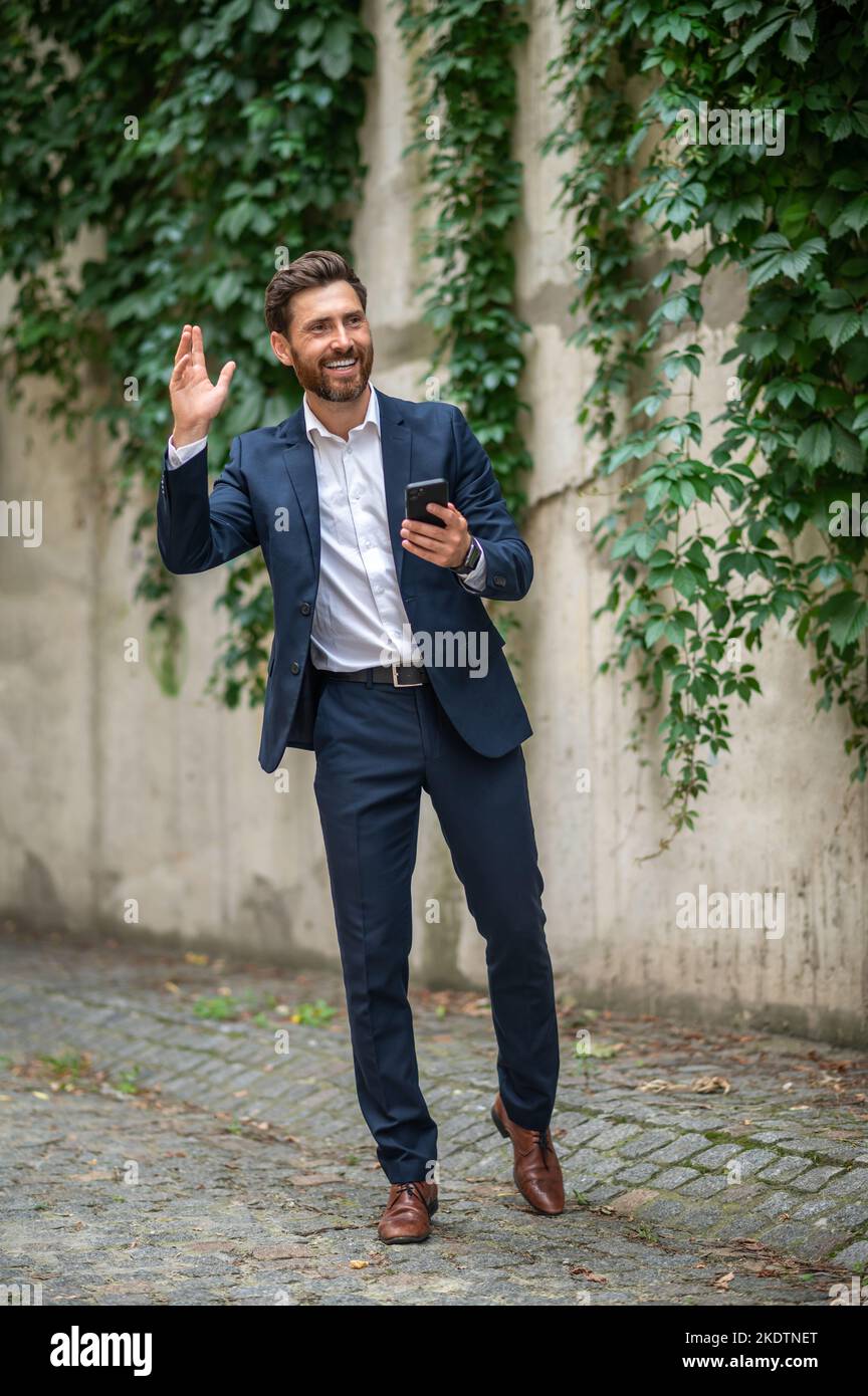 Elegant young man greeting someone and waving hand Stock Photo