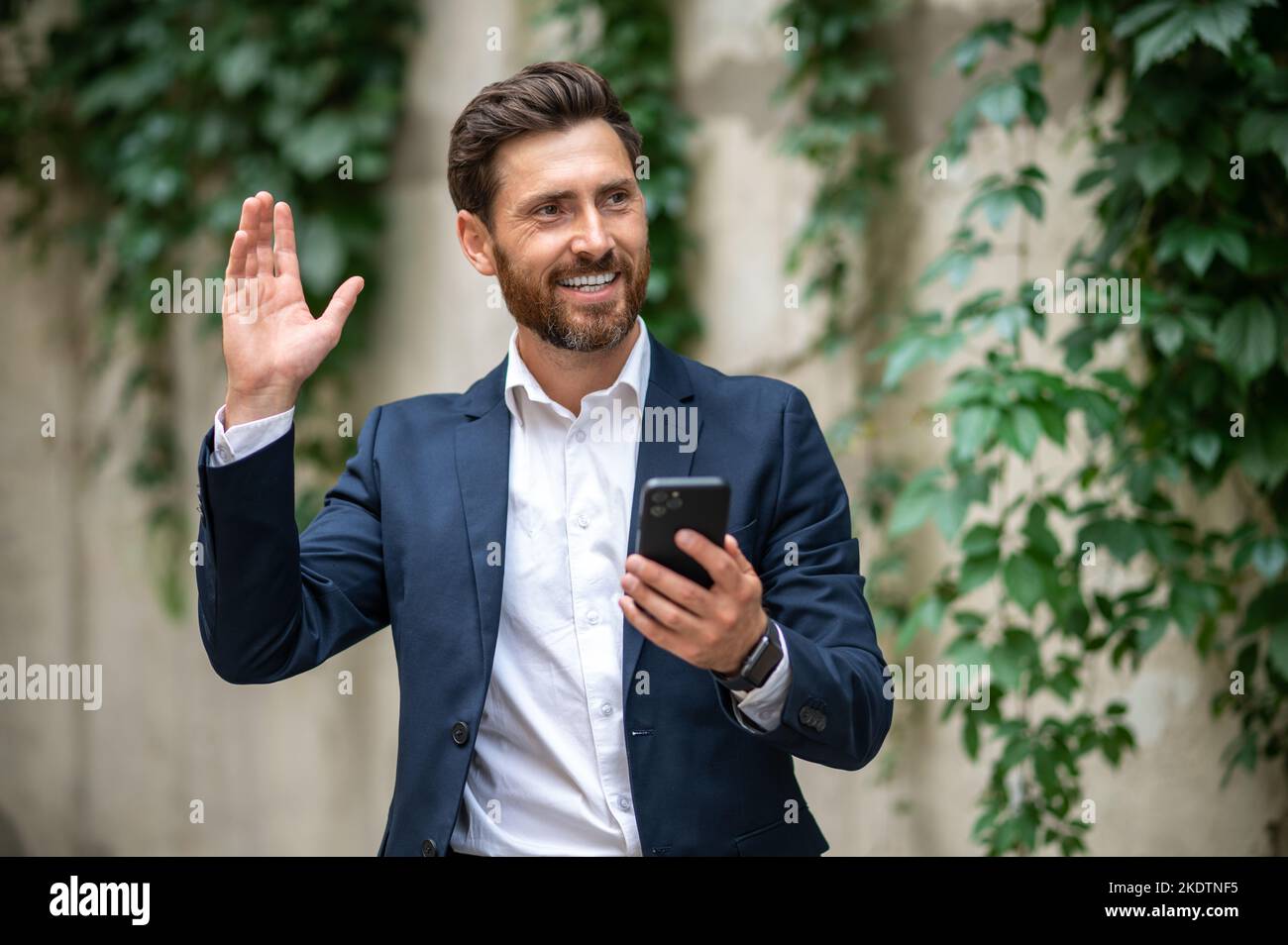 Elegant young man greeting someone and waving hand Stock Photo